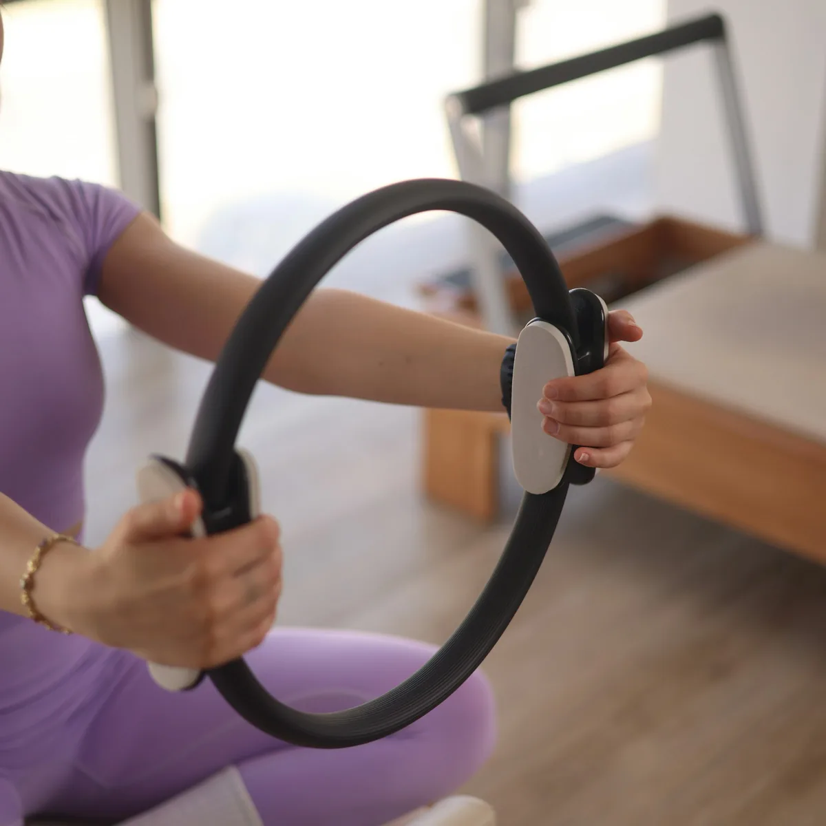 Pilates çemberini iki eliyle tutan kadın