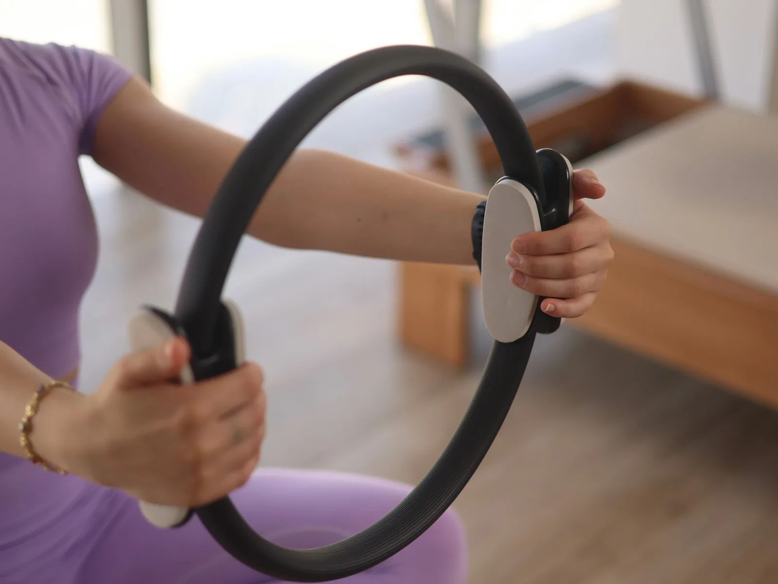 Pilates çemberini iki eliyle tutan kadın