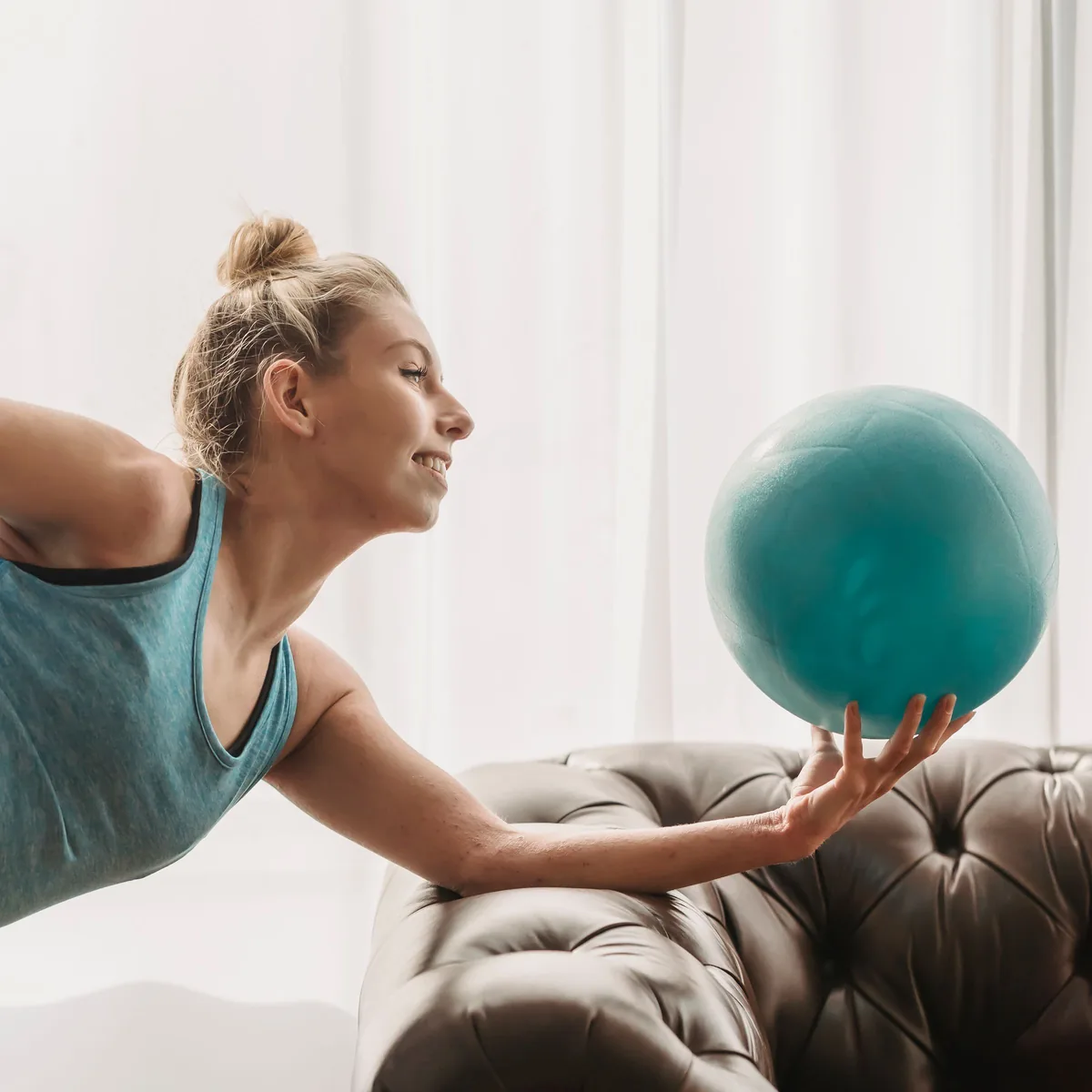 Elindeki küçük pilates topuna uzanan kadın